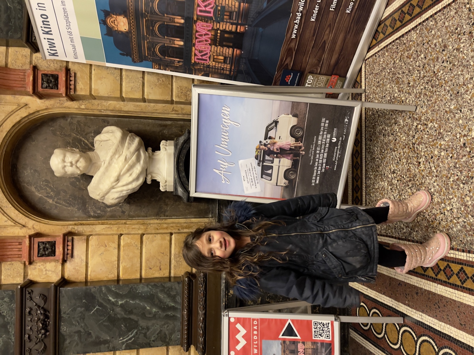 Tochter neben Filmplakat am Kino